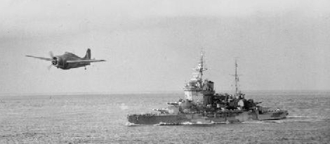 A Grumman Martlet from HMS Formidable flying near HMS Warspite